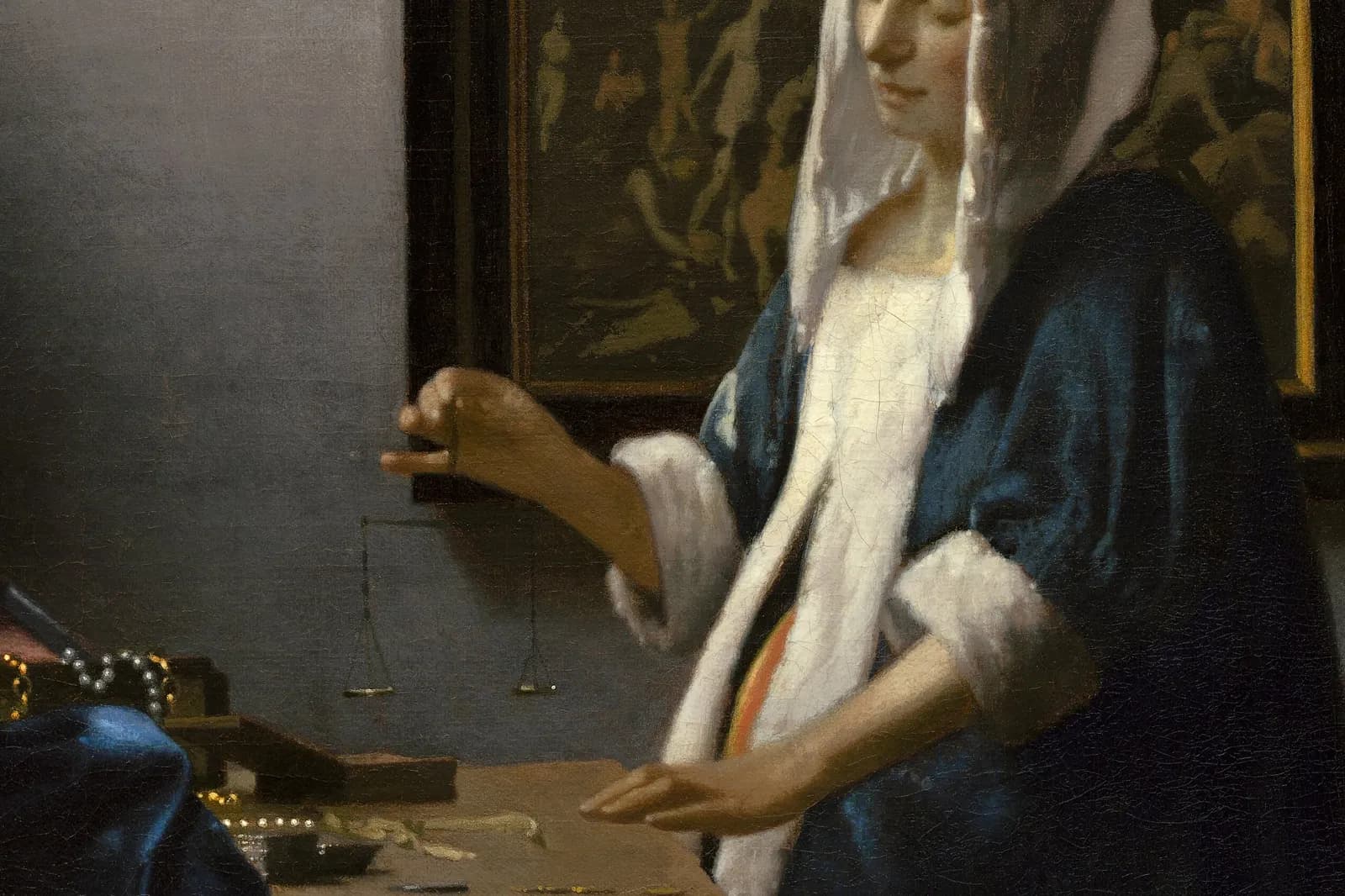 Detail of Woman Holding a Balance by Johannes Vermeer: a woman in blue holding an empty scale above a table.